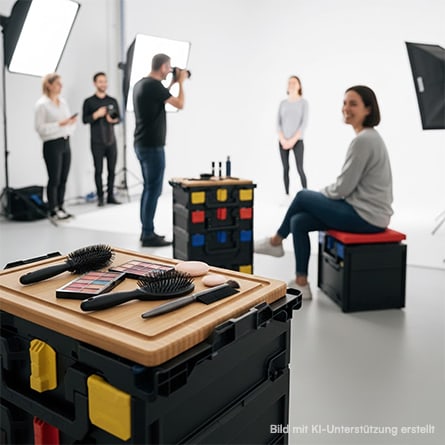 Im Fotostudio stehen zwei metaBOXen mit metaDESK, auf denen Friseurutensilien abgelegt sind. Eine Frau sietzt auf einer metaBOX mit metaSEAT.